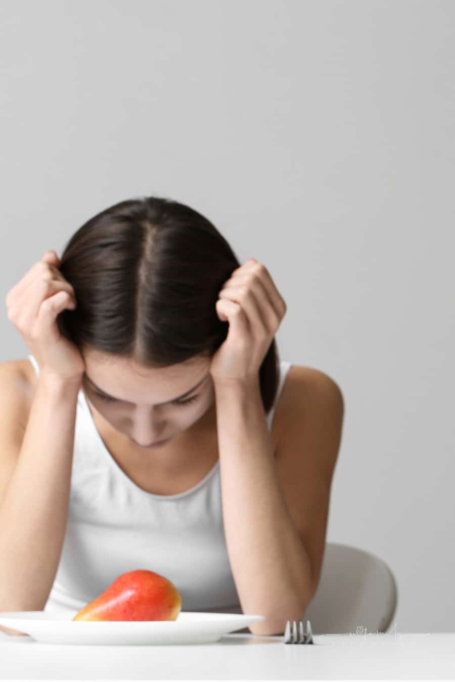 teenager struggling with eating disorder staring at food on plate
