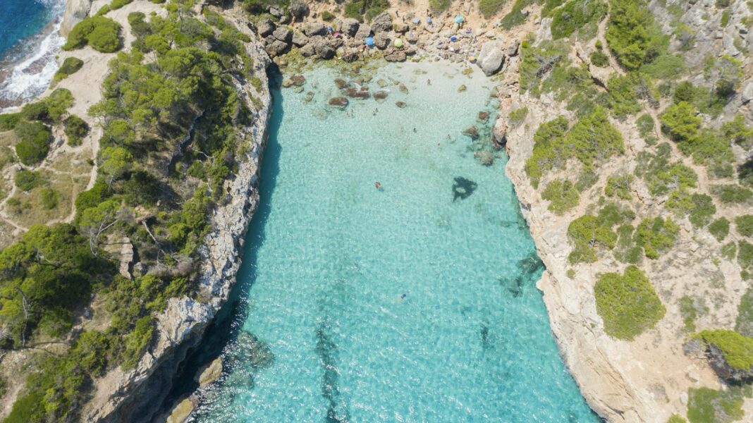 Breathtaking aerial view of Caló des Moro's turquoise waters and rocky shores in Mallorca, Spain.