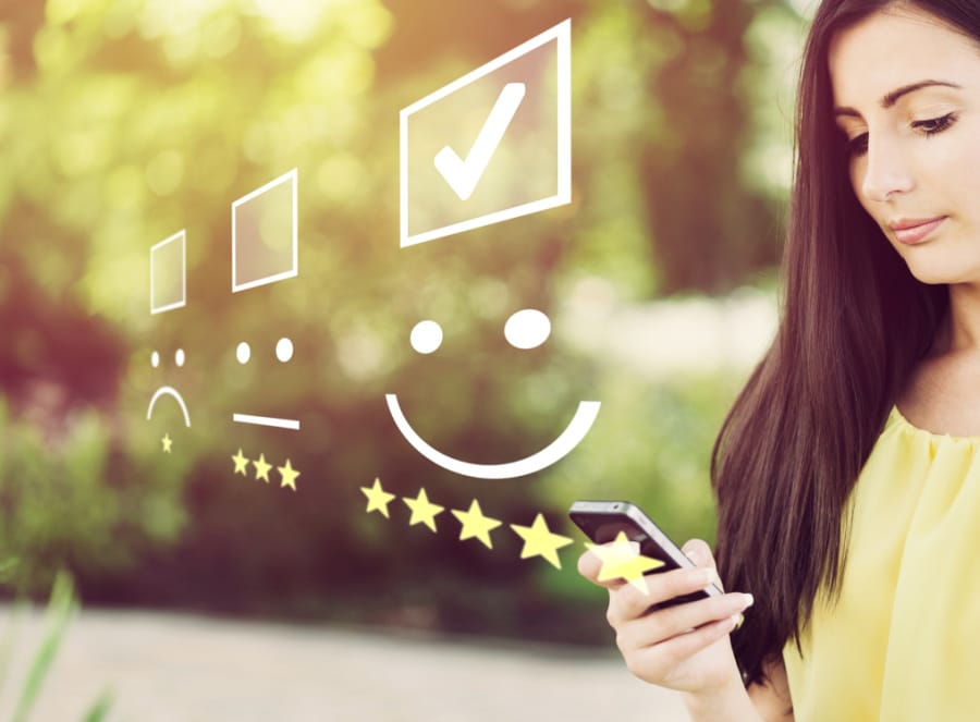 Businesswoman pressing face emoticon on virtual touch screen at smartphone .