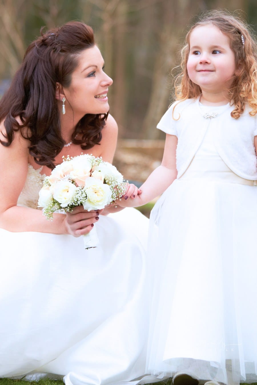 bride holding a bouquet while hoding hands with a young child