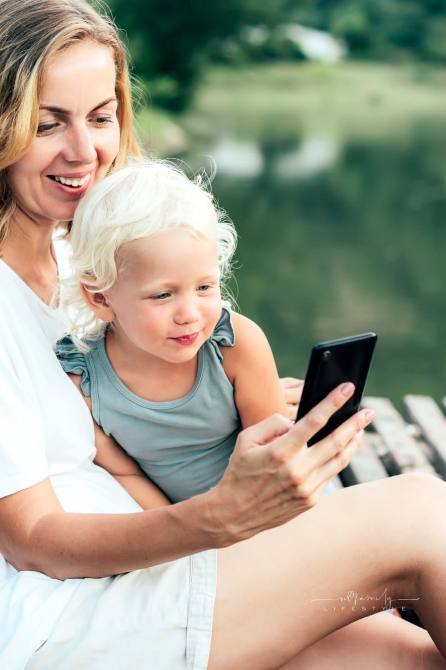 Mom and Daughter by the Lake Taking Selfie with Smartphone