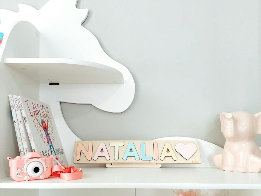 Charming child's room decor featuring unicorn shelves, pastel name sign, and toys.