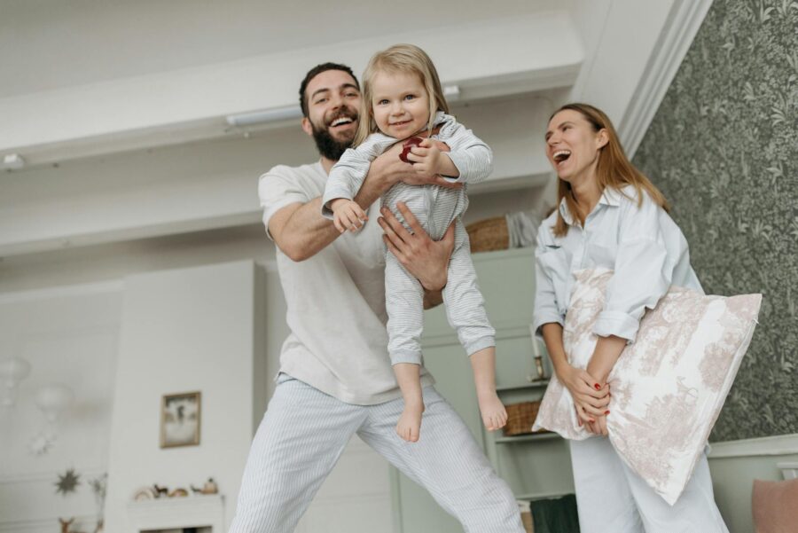 Cheerful family with parents playing and lifting child in a cozy living room.