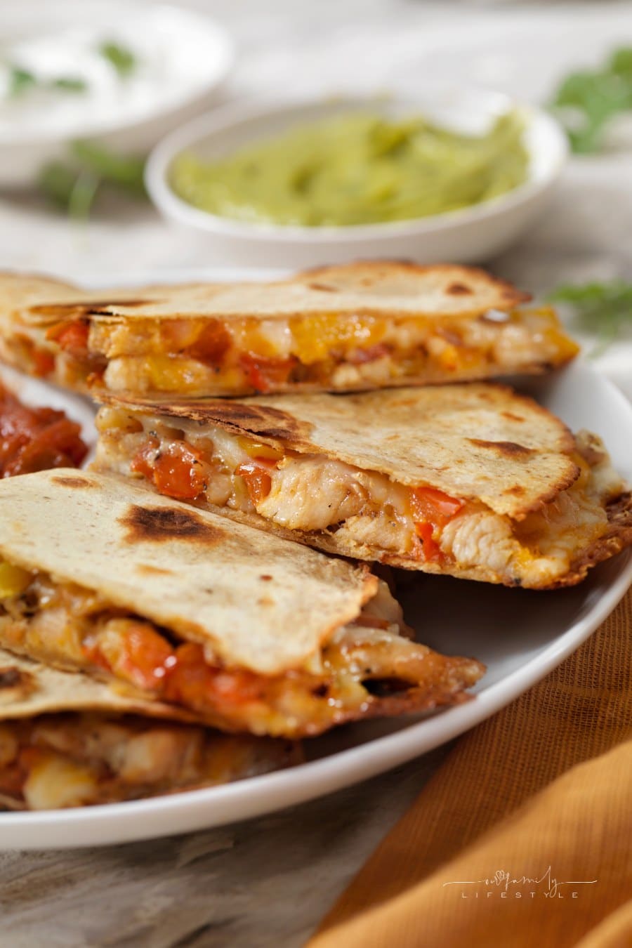 Cheesy Chicken Quesadillas on plate with bowl of guacamole in background