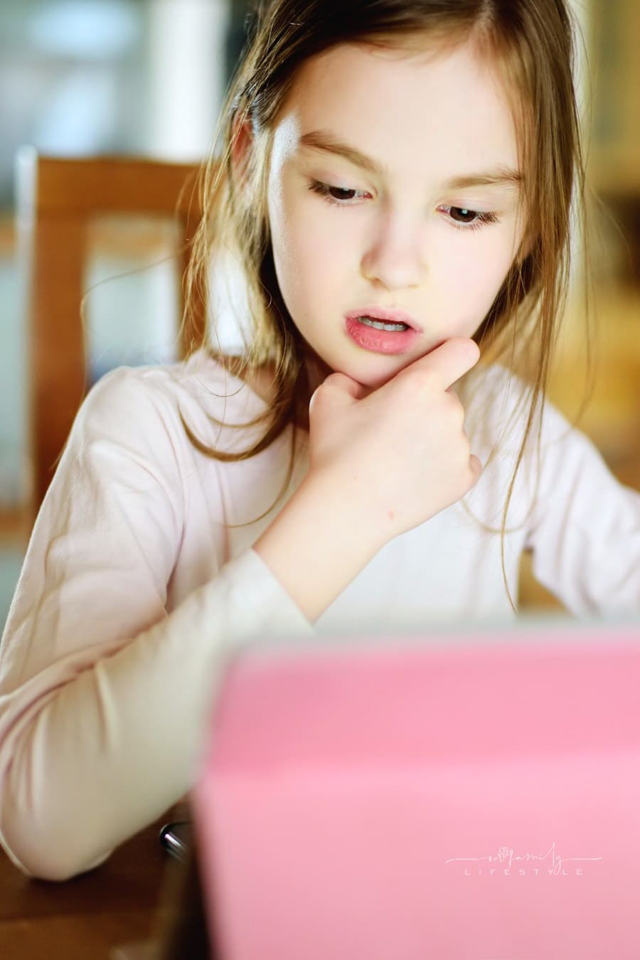 Smart Little Schoolgirl Doing Her Homework with Digital Tablet at Home. Child Using Gadgets to Study.