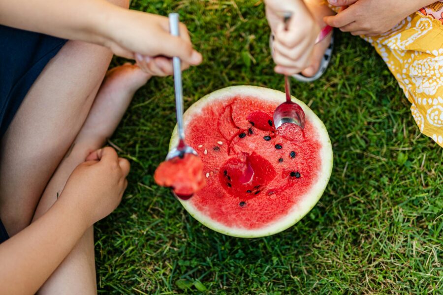 Children enjoying a fresh watermelon outdoors in the summer. A vibrant, healthy snack.