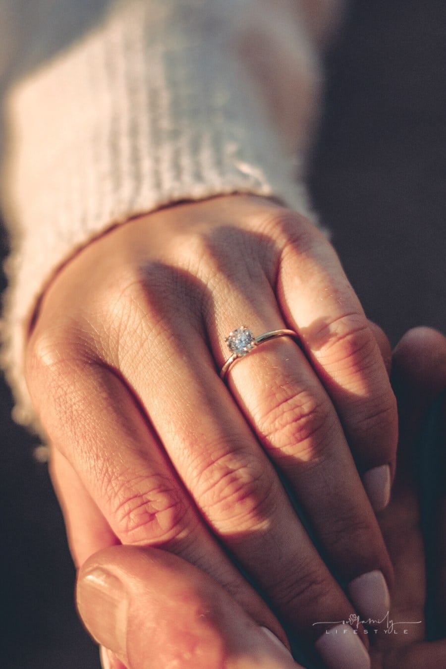 close-up of woman wearing an engagement ring while holding man's hand