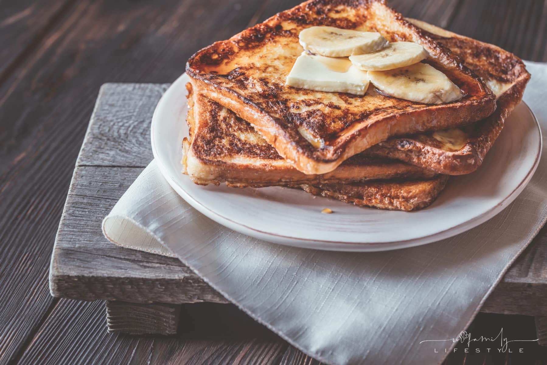 classic french toast topped with syrup and bananas