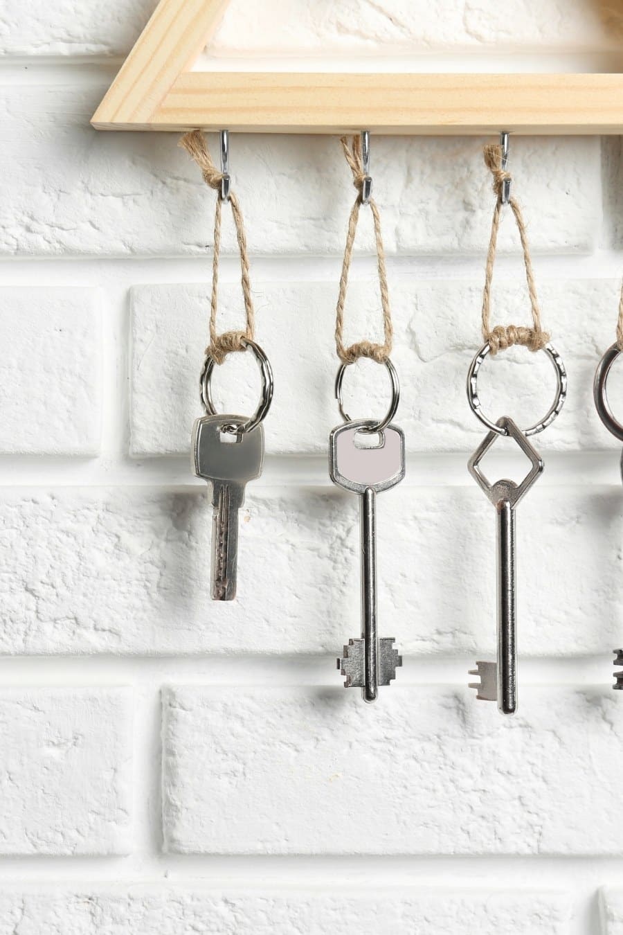 Wooden Key Holder on White Brick Wall Indoors, Closeup.