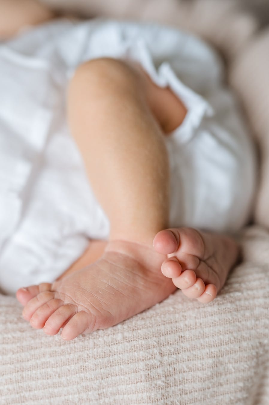 Close-up of a baby's tiny feet resting peacefully on a soft blanket indoors.