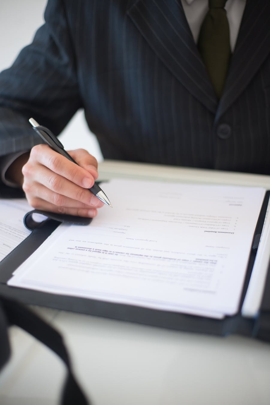 Close-up of a business professional signing documents in an office setting.