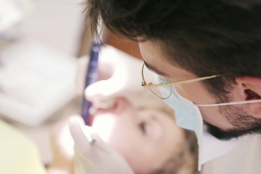 Close-up of a dentist in a face mask performing a dental procedure on a patient indoors.