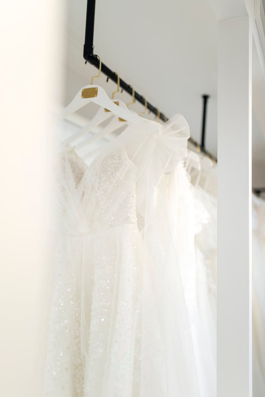 Close-up of beautiful white wedding dresses hanging in a bridal shop, showcasing elegant design.