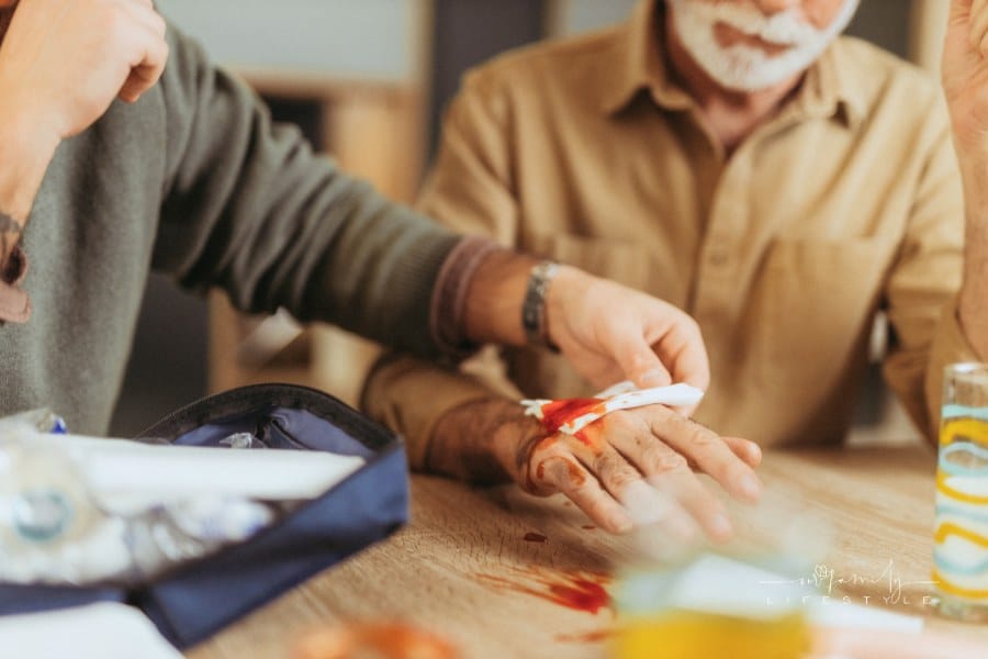 Man bandaging senior father's bleeding hand
