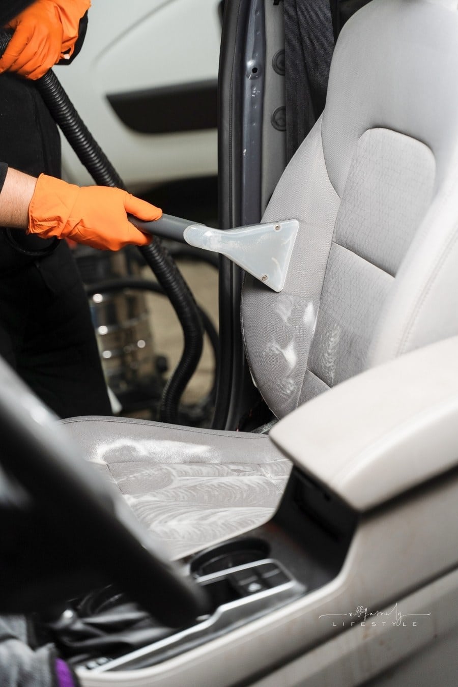 Car cleaner is extracting dirt from car seat using dry cleaning extractor machine. Cleaning textile seats in car interior using extractor machine for dry clean.
