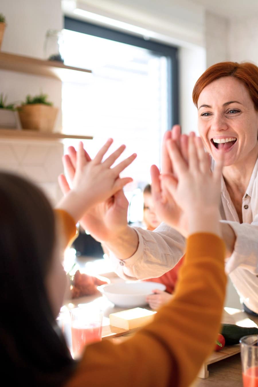 Happy Mother of Three Little Children Preparing Lunch Boxes in Kitchen at Home, mother high-fiving daughter in kitchen