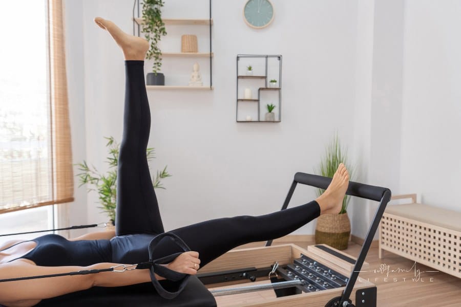 Woman Exercising on Pilates Reformer Bed at home
