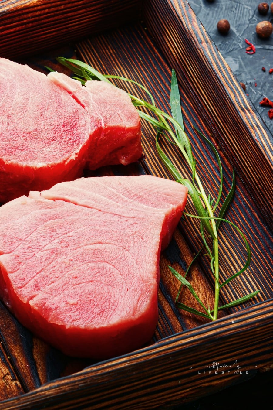 Fresh raw tuna steak and tarragon on kitchen table