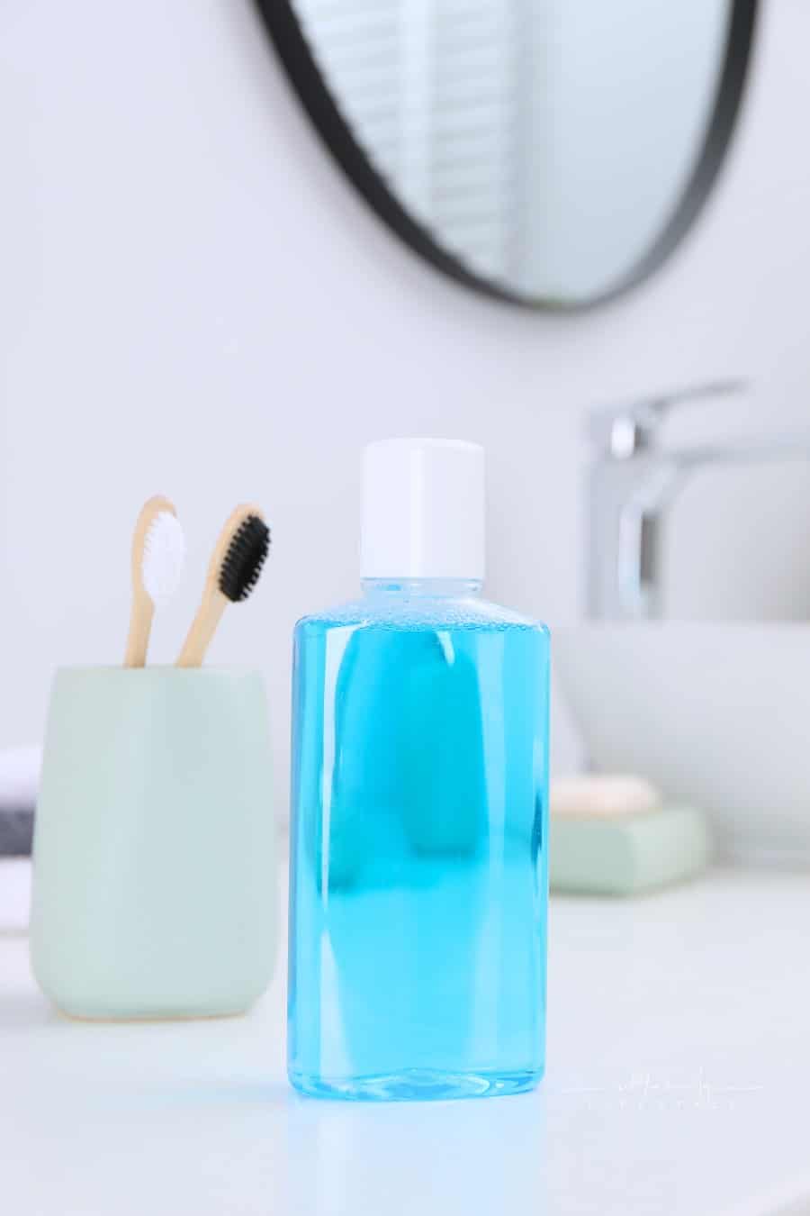 Bottle of Mouthwash and Toothbrushes on White Table in Bathroom