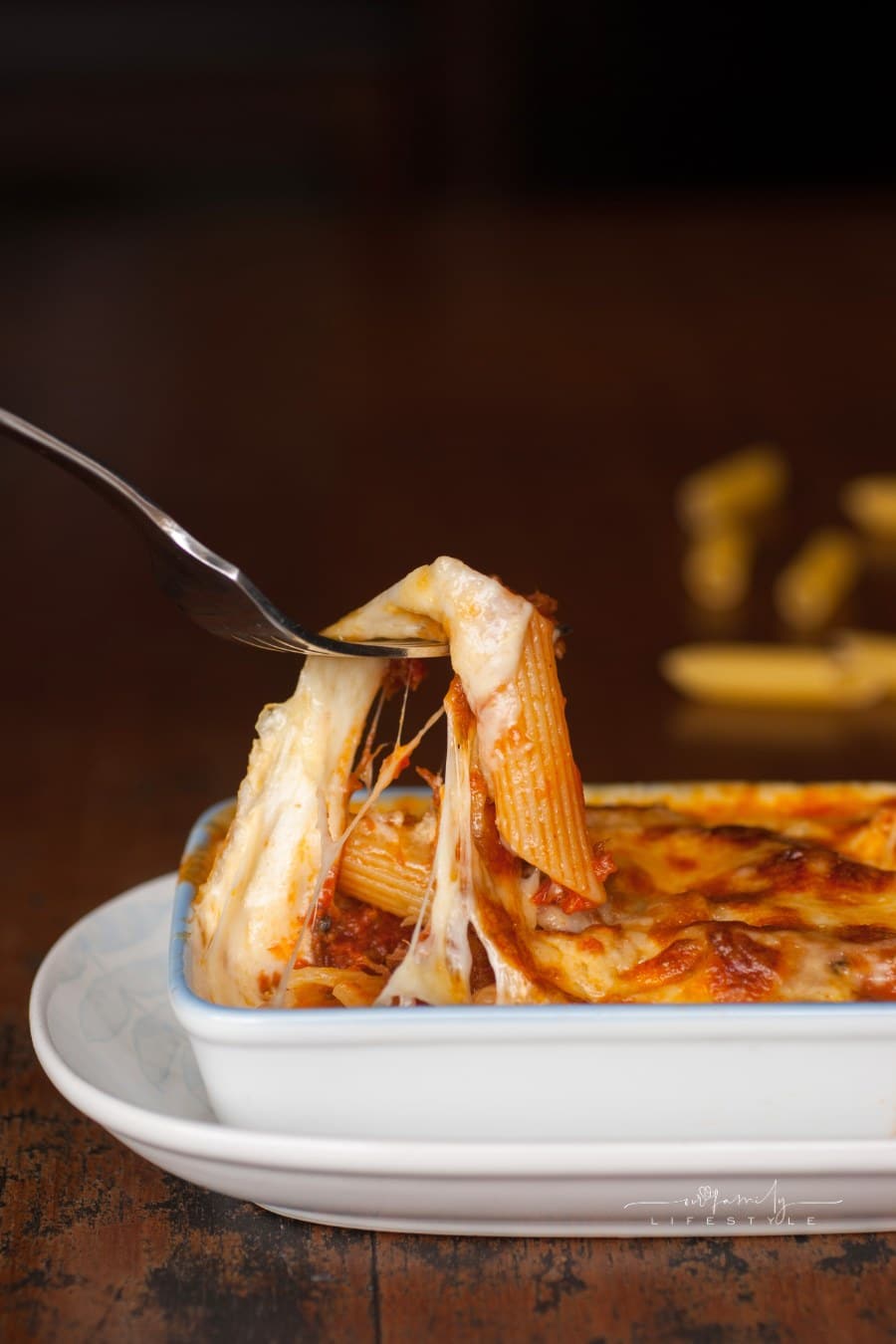 Baked penne pasta with tomato sauce and cheese in white bowl
