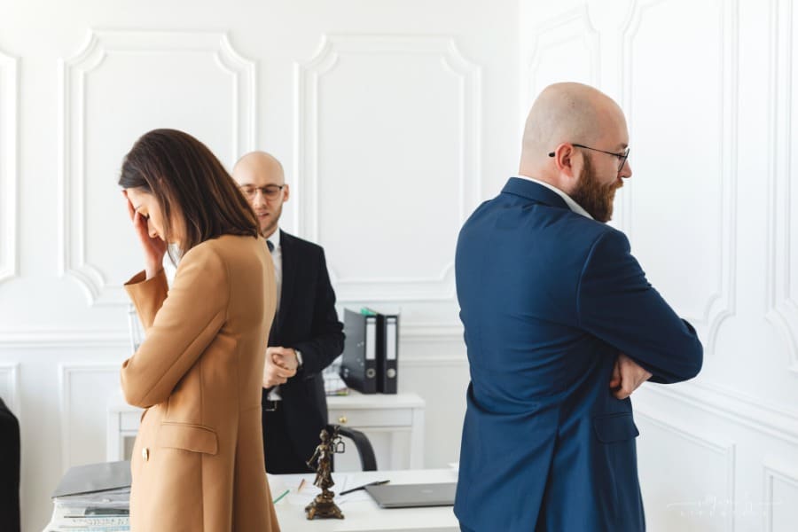 couple standing with backs towards each other in divorce lawyers office