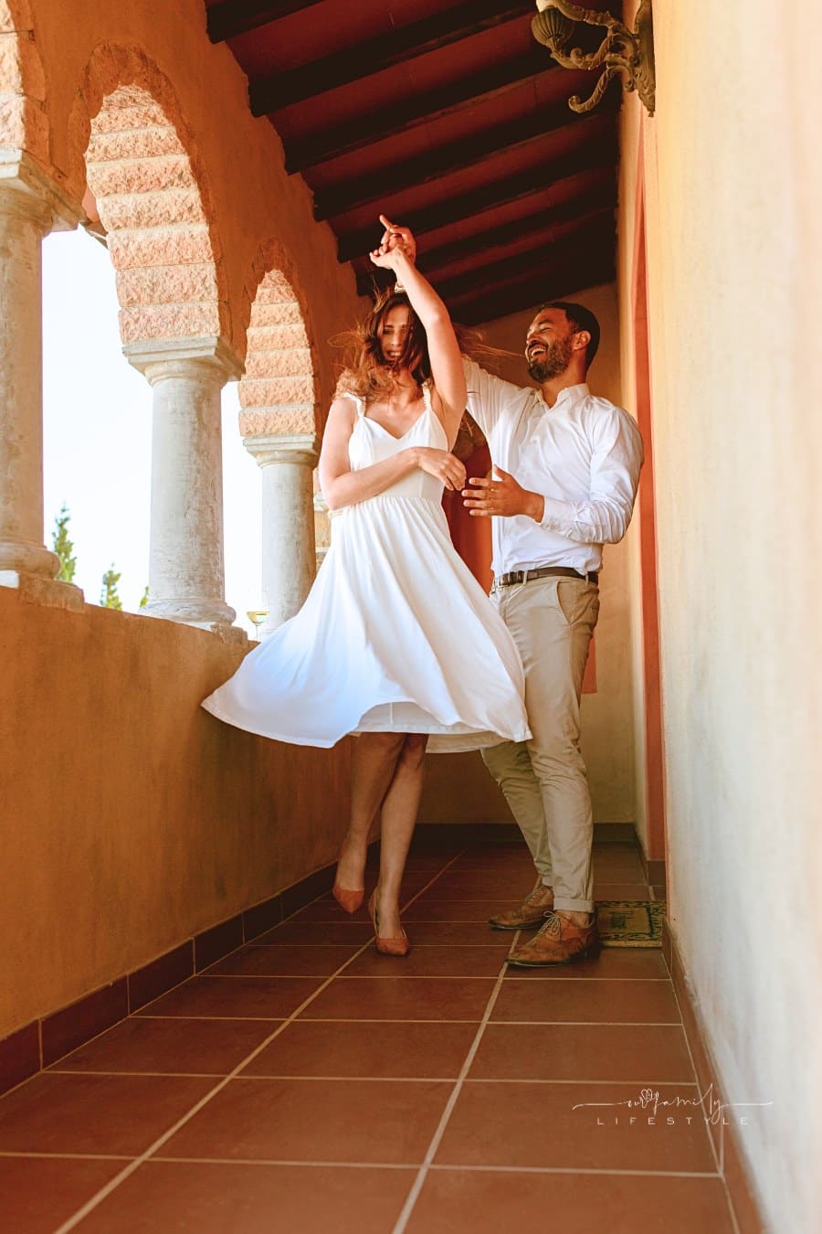 Happy couple dancing in the balcony of a building. Smiling man and woman on a date dancing together.