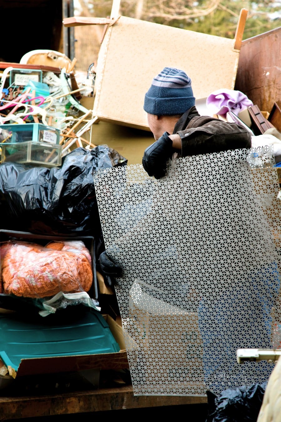 Workman loading dumpster with junk