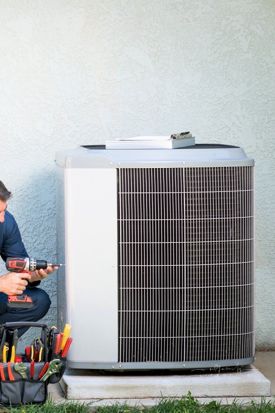 Air conditioner repairman in uniform working in outdoor HVAC system.