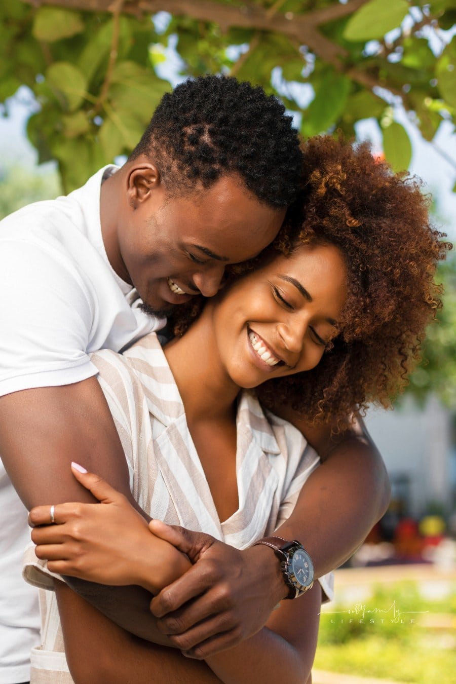 couple embracing with man holding woman from behind; happy couple