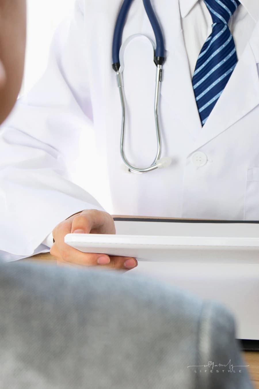 doctor looking at tablet while talking to patient