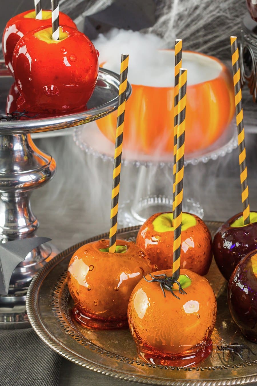 candied apples on a party table with a smoking pumpkin in the background