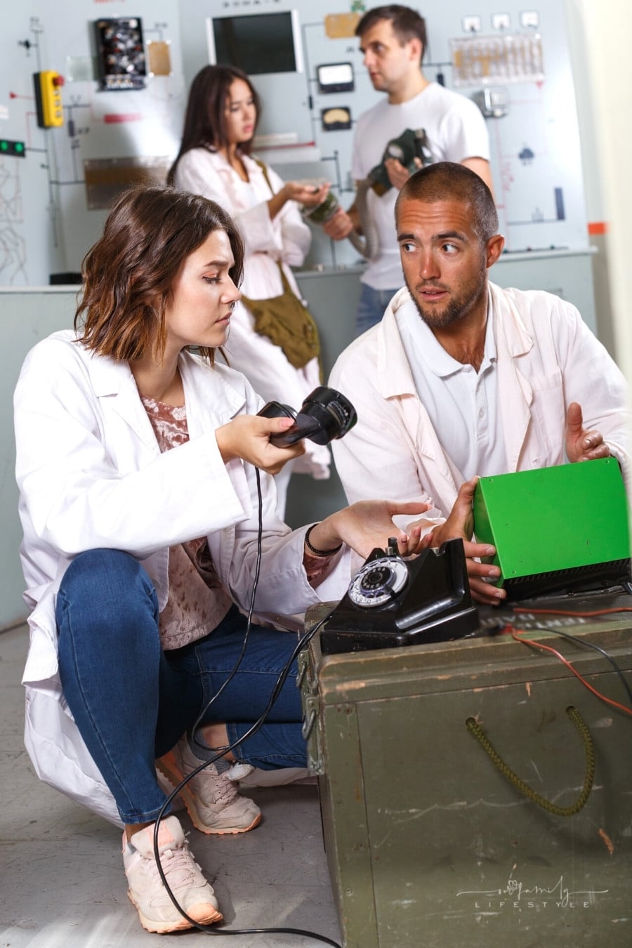 man and woman looking at rotary phone trying to solve escape room stylized as underground shelter