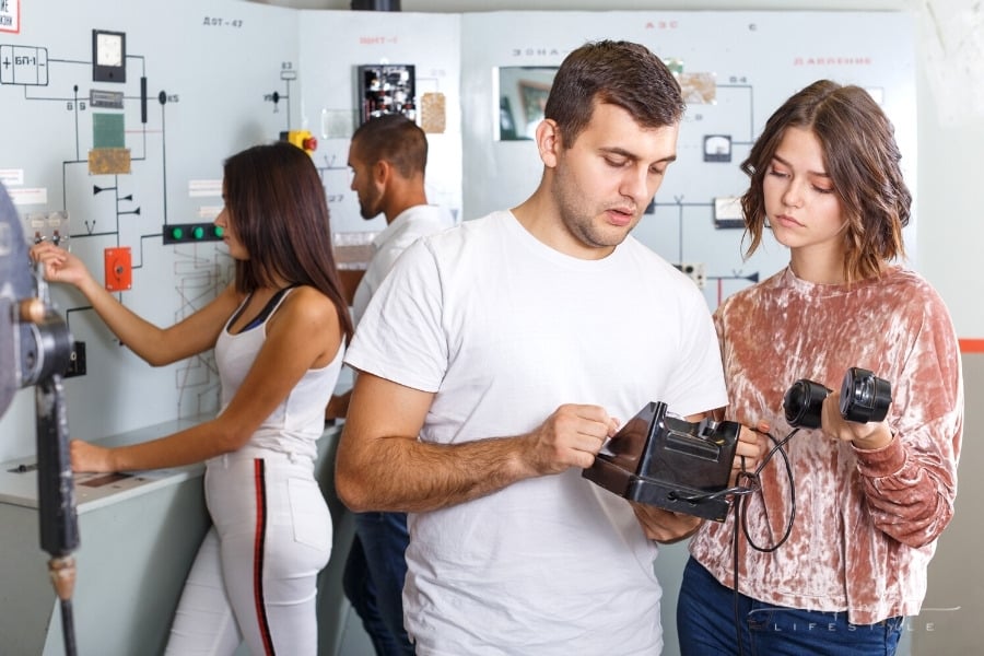 man and woman looking at rotary phone trying to solve escape room puzzle