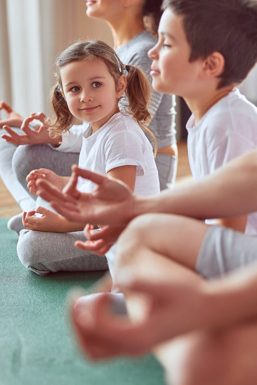 Happy little girl practicing meditation with family