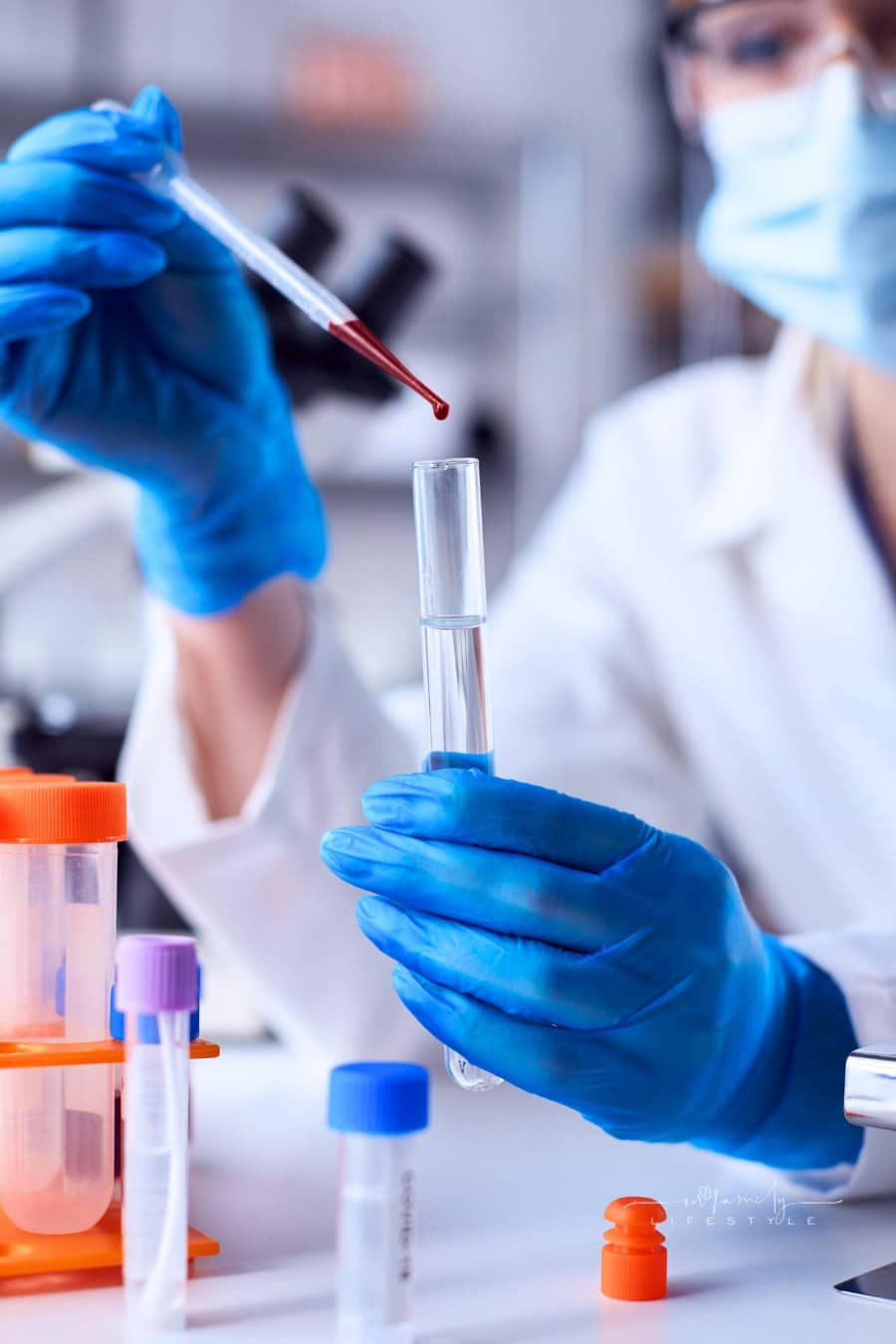 Female Lab Research Worker Wearing White Coat Putting Blood Sample from Pipette into Test Tube