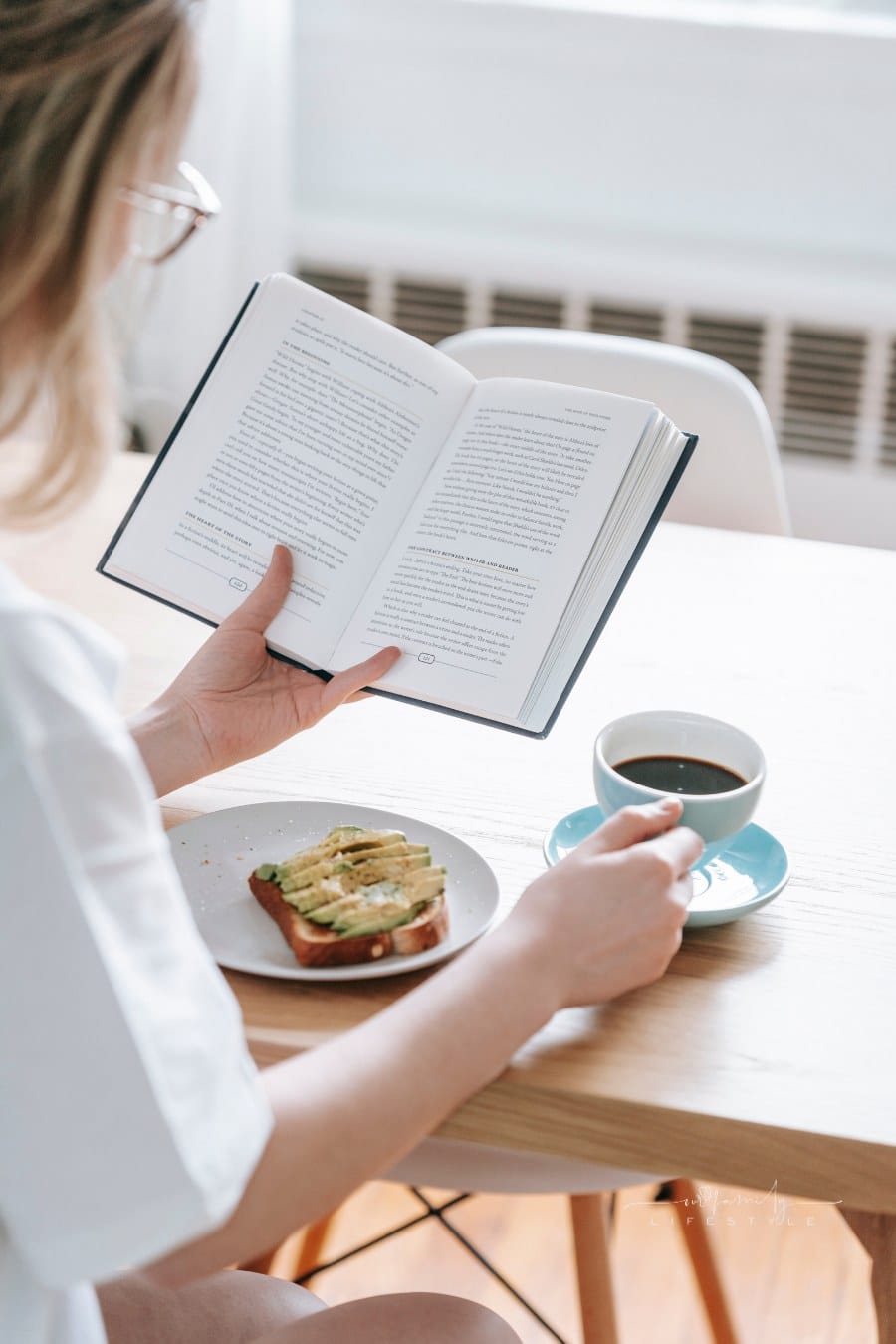 Crop woman with cup of coffee and book