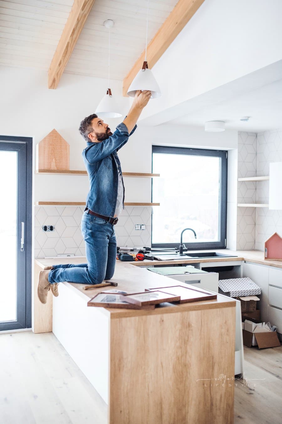 A Mature Man hanging pendant lights in New House, a New Home Concept.