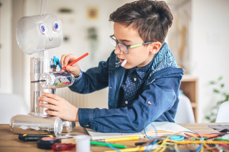 young boy making robot toy from recycled material