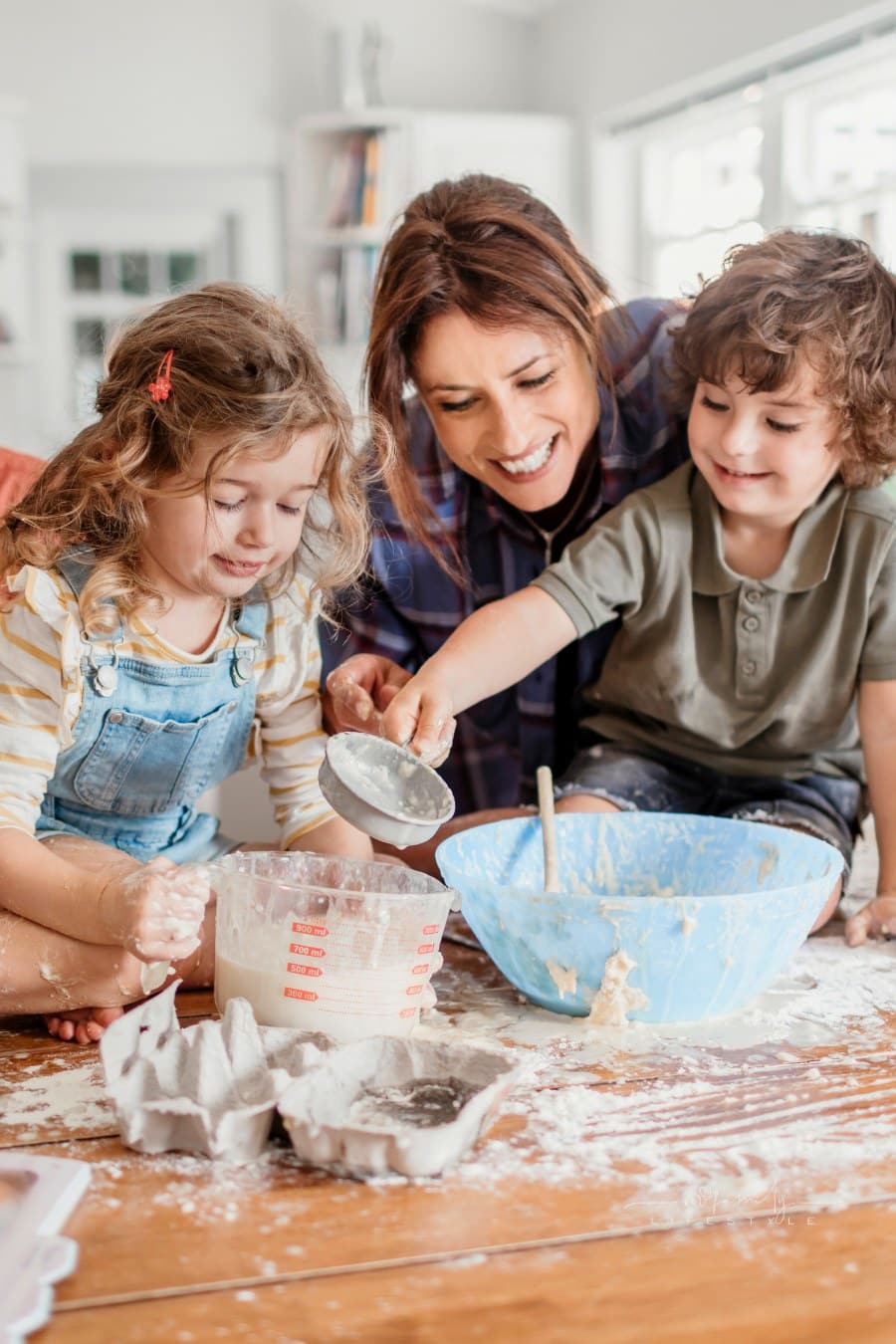 Young family baking together in kitchen covered in baking ingredients