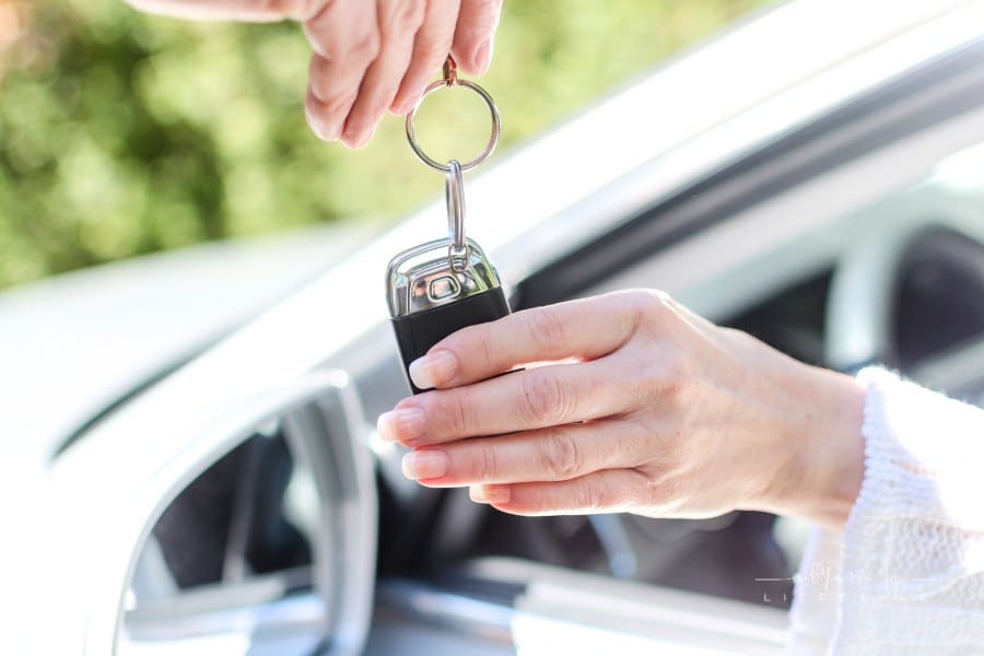 Man giving car key to a woman inside vehicle