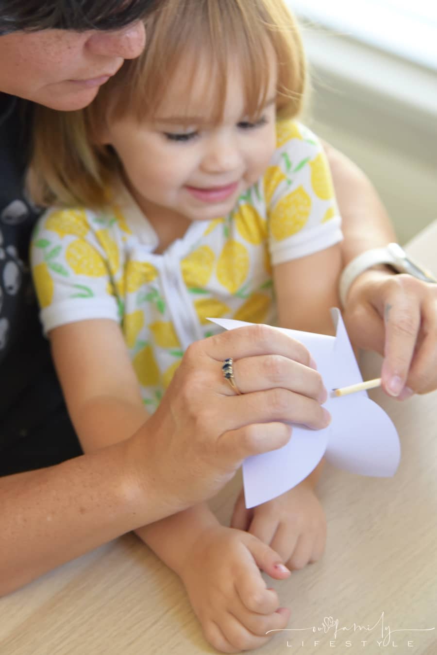 grandma and toddler making paper pinwheels with thumbtack
