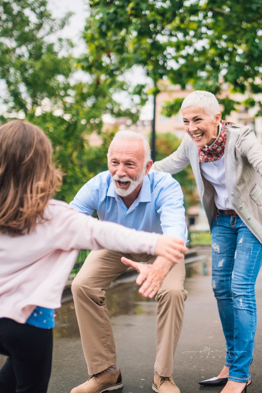 grandparents at the park ready to catch granddaughter running towards them