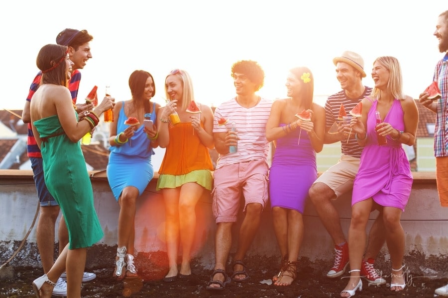 group of young people enjoying a rooftop summer party with food and drinks