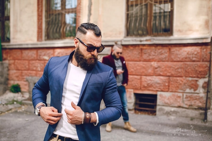 two bearded men posing in front of building