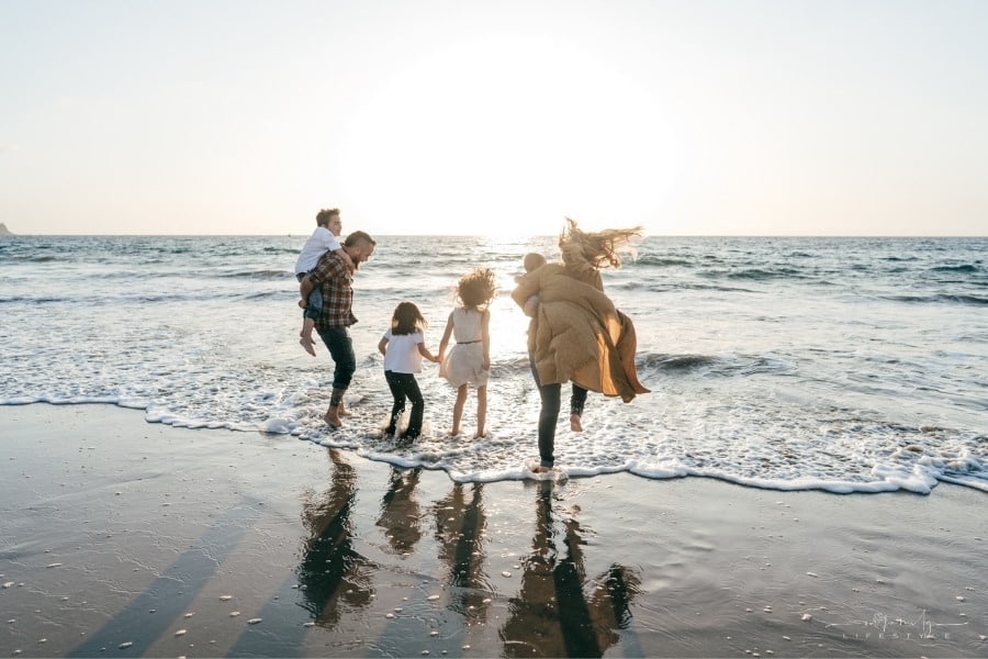 family running and jumping waves on sunset beach