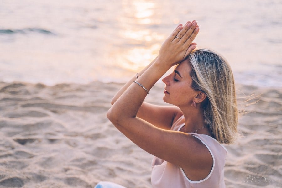 woman praticing mindfulness through yoga on a beach