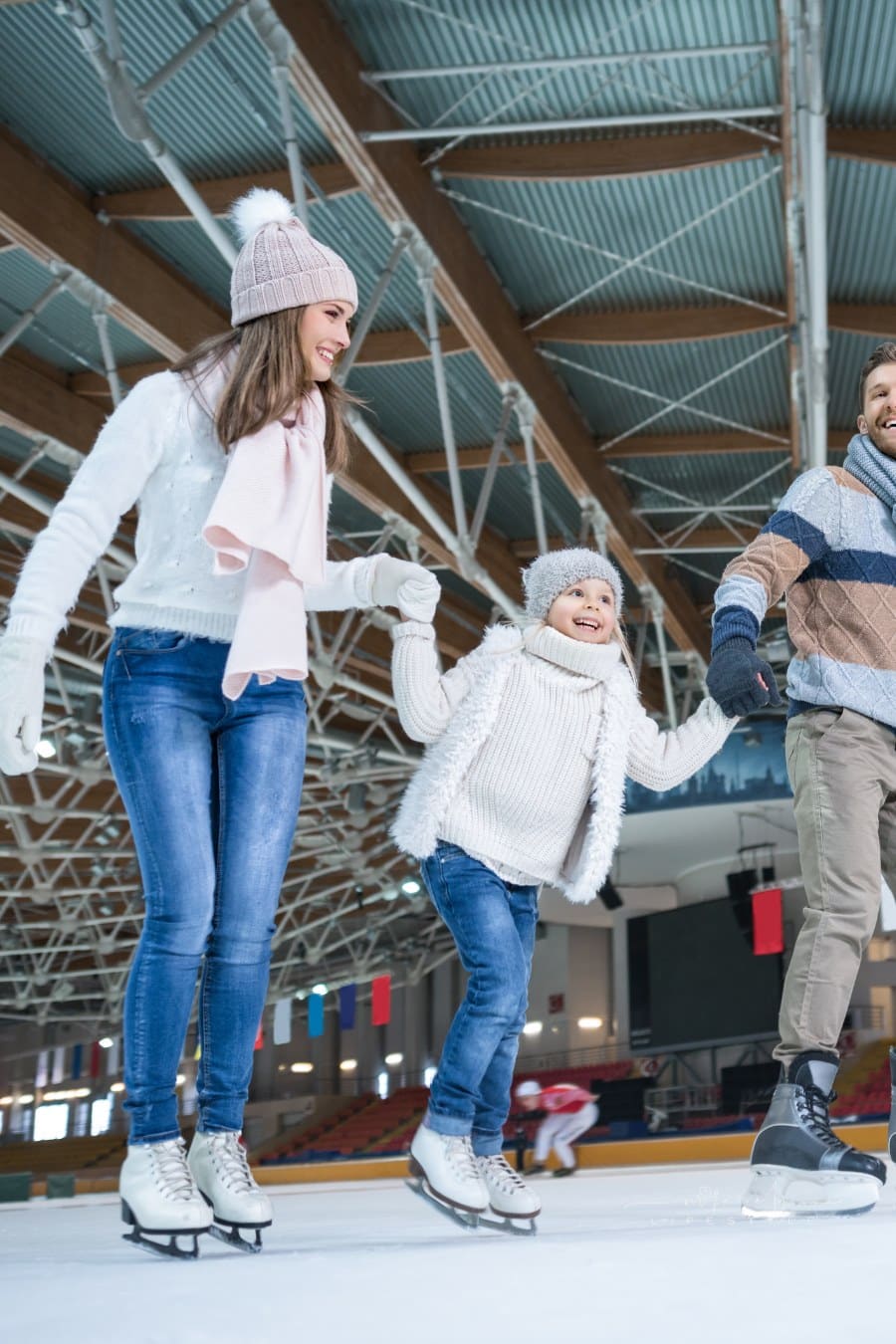 family ice skating happily together at an indoor rink