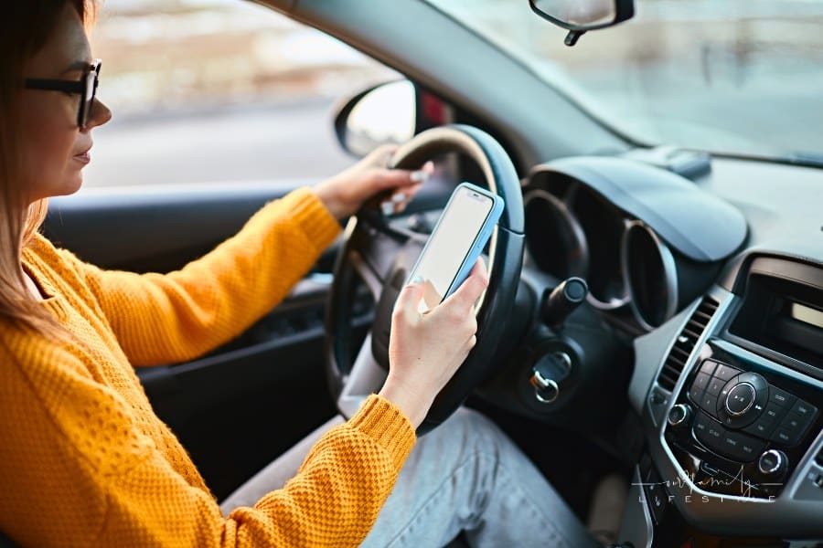 Young woman driver using mobile phone while driving car, unsafe driving