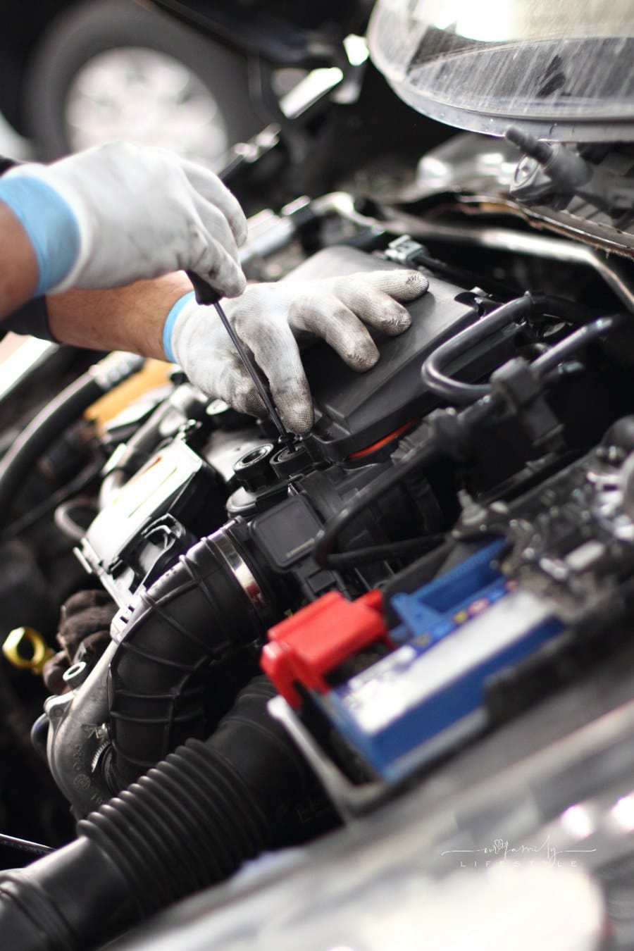 mechanic working under hood of car