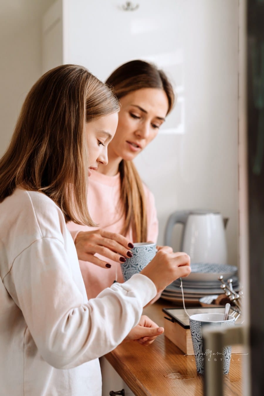 Mother and Daughter Talking while steeping and Drinking Tea in Kitchen